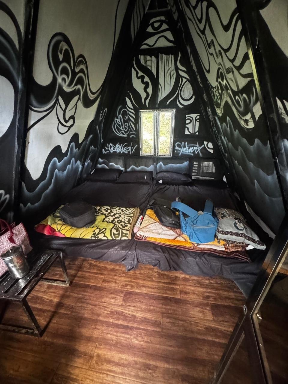 Painted interior of an A-frame hut with mattress bedding